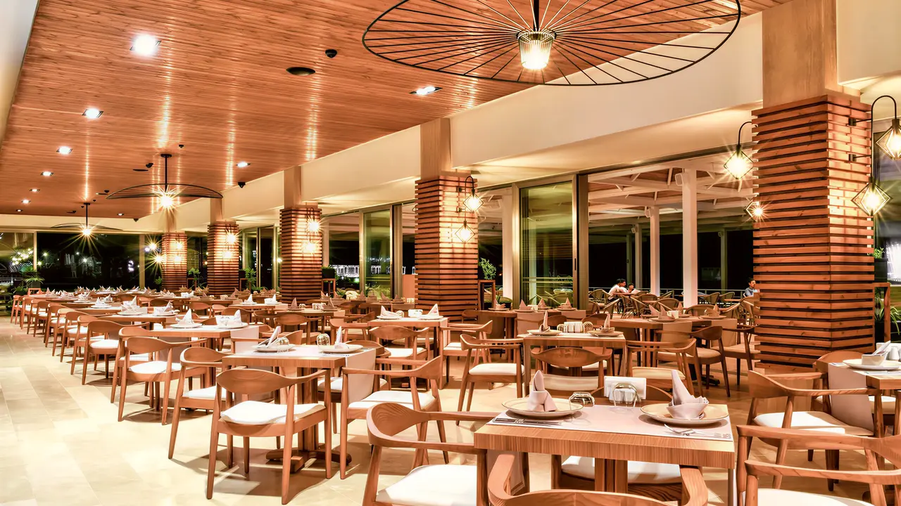 Restauracja w Acapulco Resort (Kyrenia) z drewnianymi stołami i krzesłami