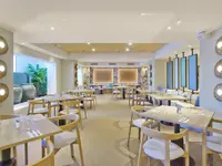 Jasna restauracja w Aparthotel Sunset Beach Club z drewnianymi stołami