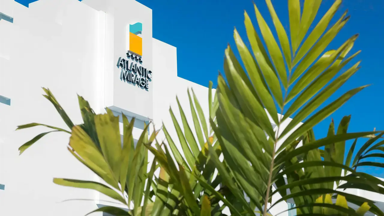 Biała fasada budynku Atlantic Mirage Suites & Spa i palmy