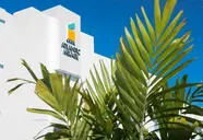 Biała fasada budynku Atlantic Mirage Suites & Spa i palmy