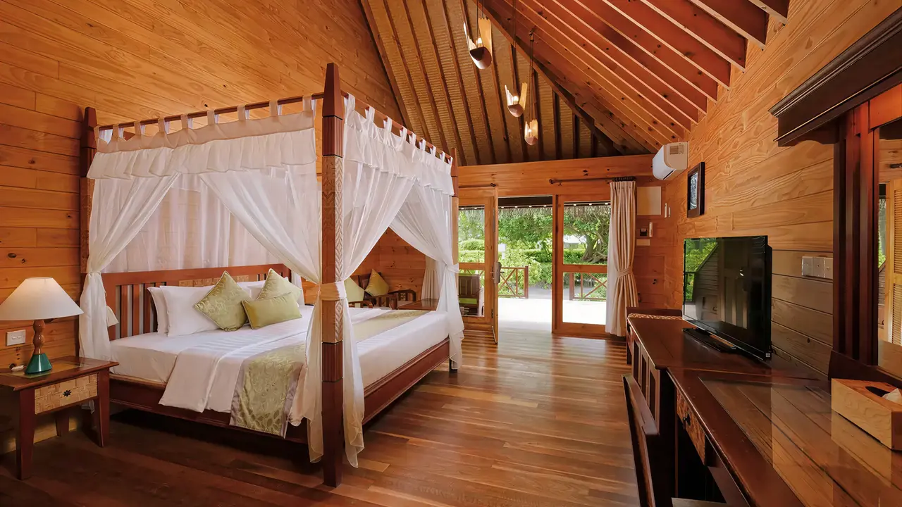 Drewniana sypialnia z łóżkiem w Bandos Maldives
