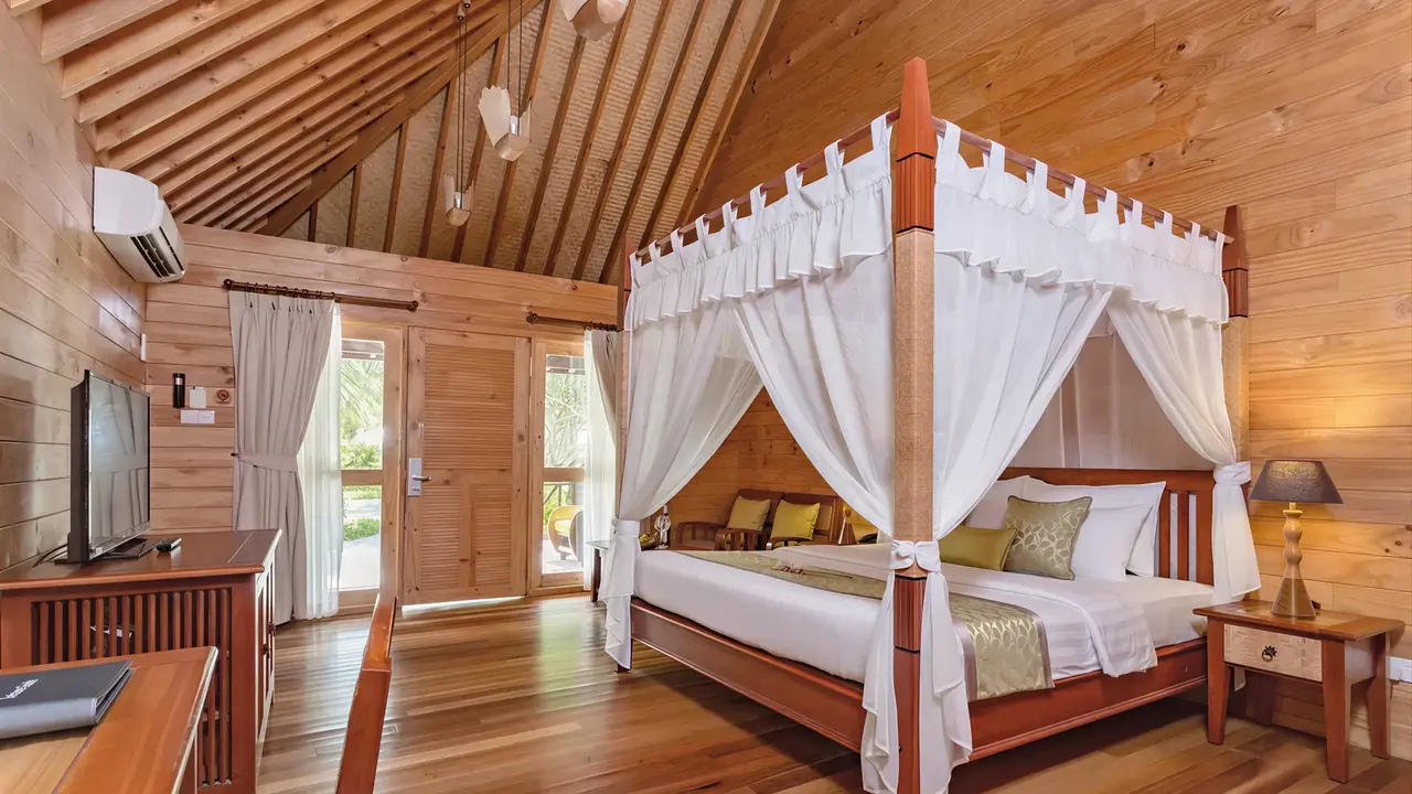 Drewniana sypialnia z łóżkiem w Bandos Maldives