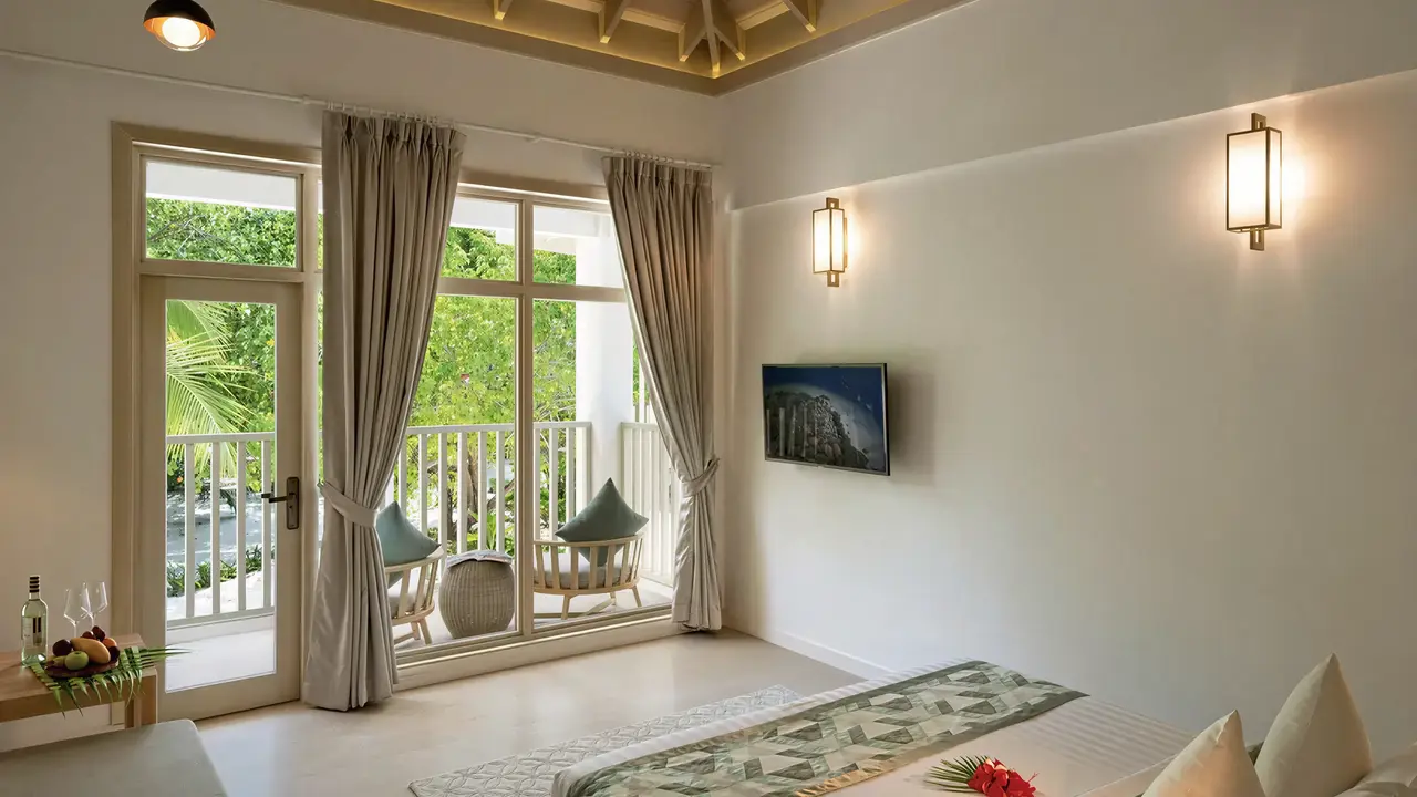 Wnętrze jasnego pokoju w Bandos Maldives z balkonem