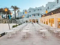 Taras restauracyjny w Blue Sea Corralejo Village z białymi stolikami