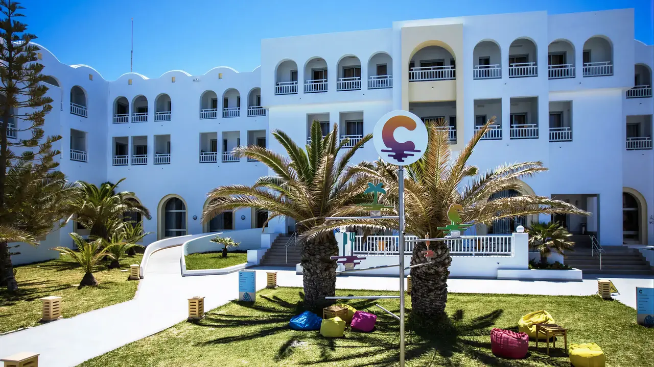 Biały budynek Club Calimera Yati Beach z palmami i trawnikiem