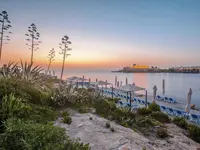 Leżaki i parasole przy plaży w Corinthia St. George's Bay