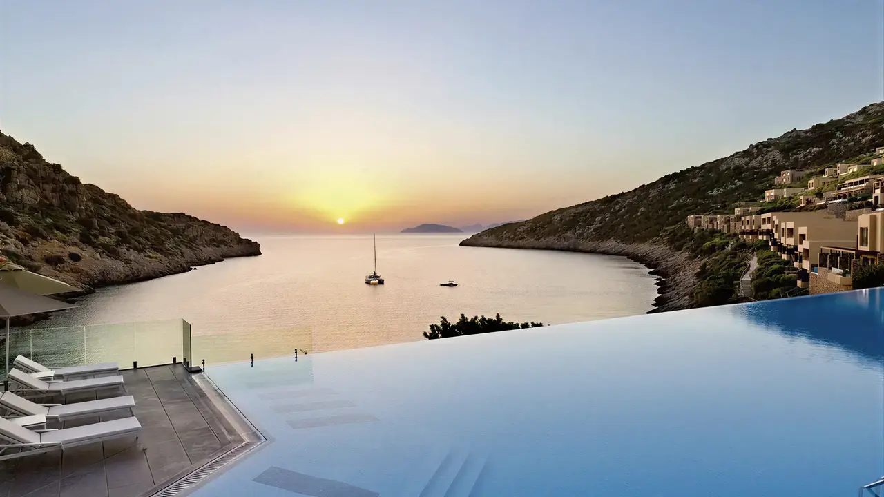 Basen typu infinity w Daios Cove Luxury Resort & Villas o zachodzie słońca