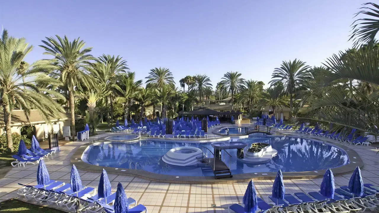 Basen z niebieskimi leżakami w Dunas Suites & Villas Resort
