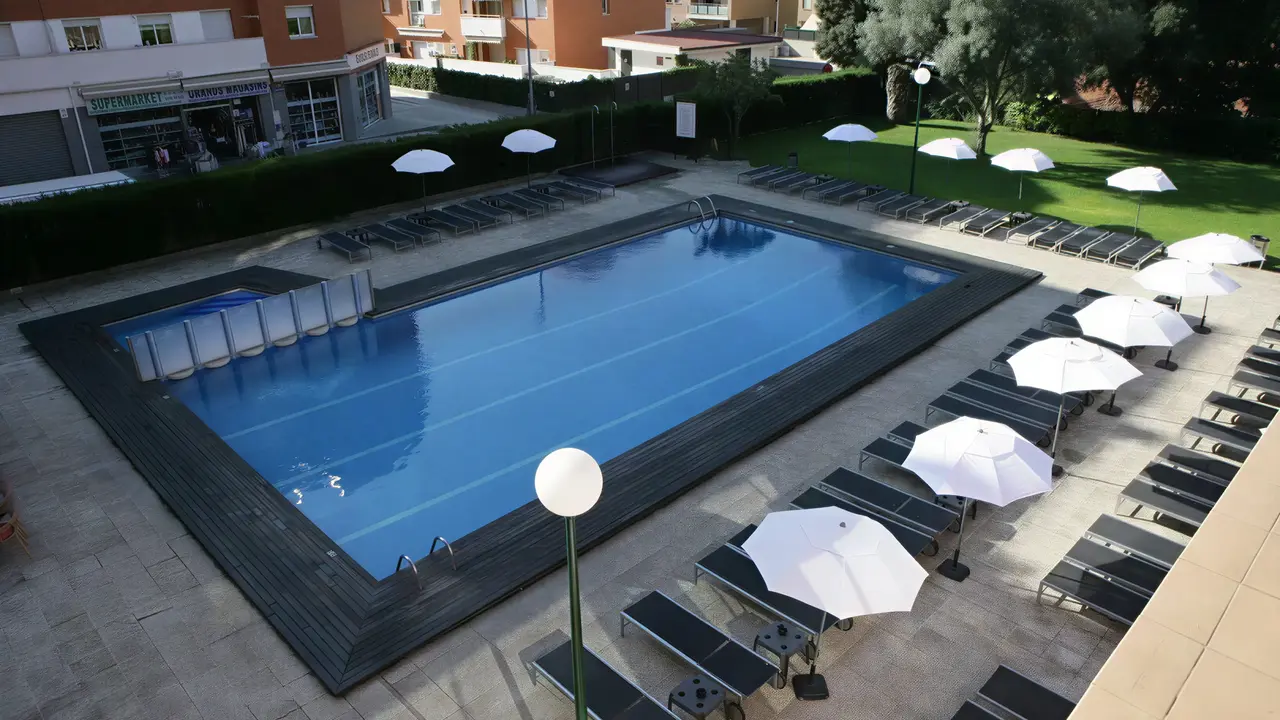 Basen z leżakami i parasolami w Fenals Garden