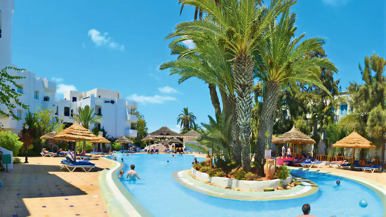 Basen z leżakami i palmami w Fiesta Beach