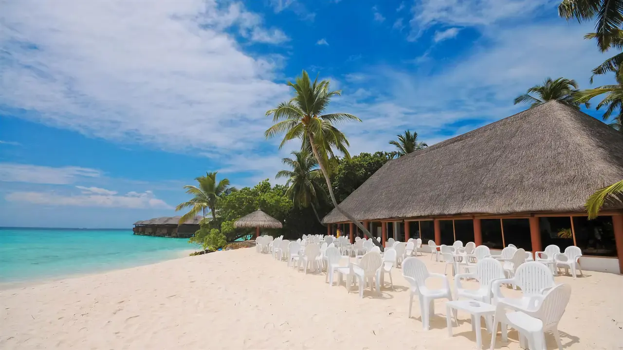 Biała plaża z białymi meblami w Fihalhohi Island Resort