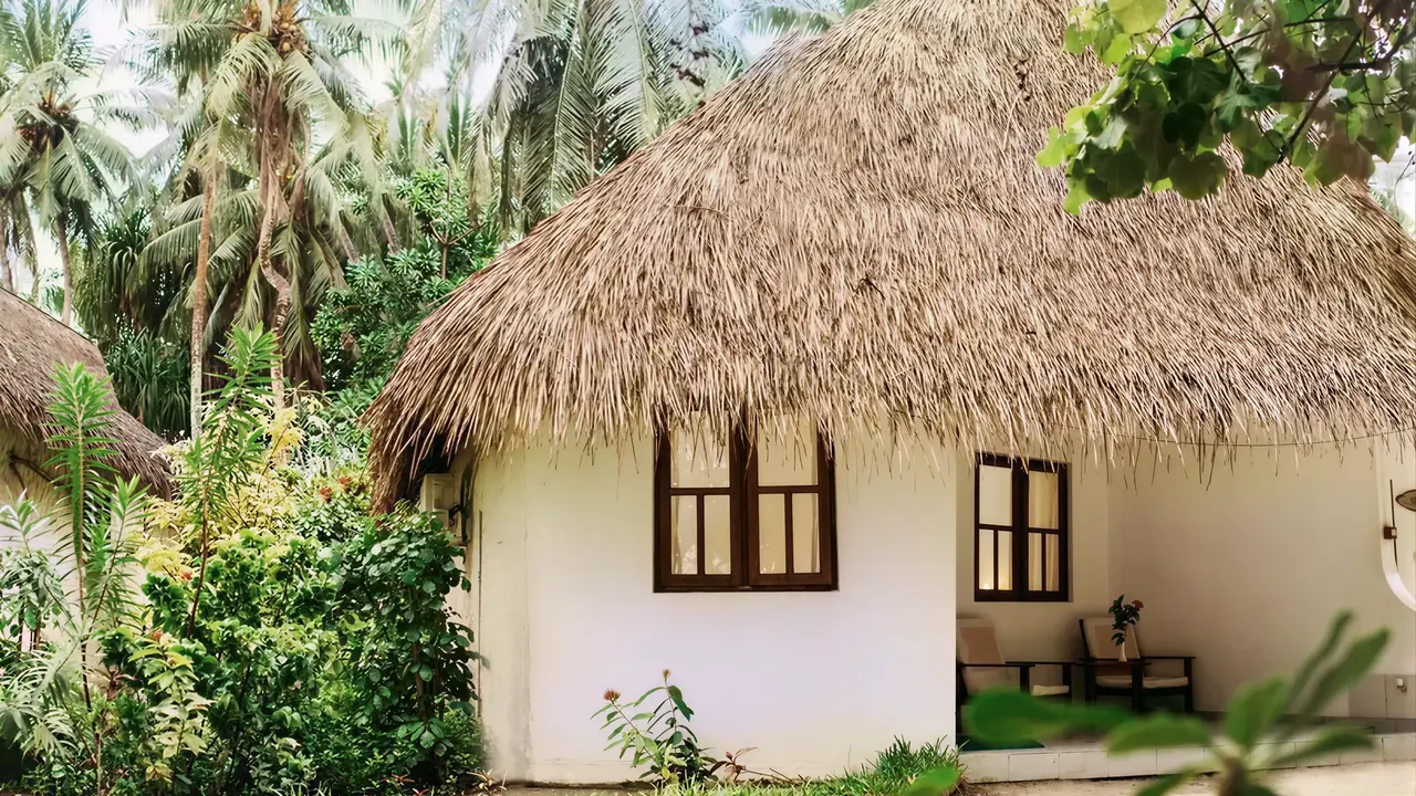 Biały domek z krytym dachem w Fihalhohi Island Resort