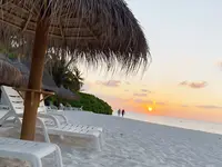 Plaża z leżakami w Fihalhohi Island Resort o zachodzie słońca