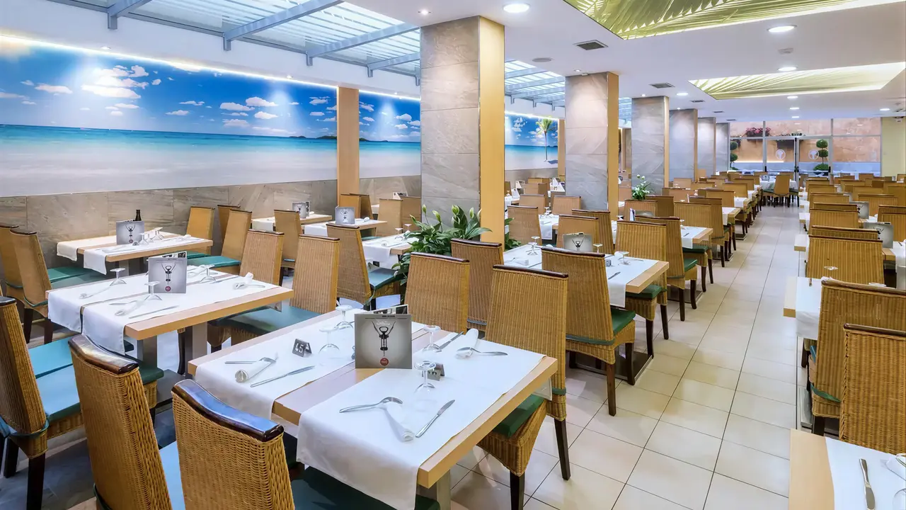 Jasna restauracja w hotelu GHT Oasis Tossa z ustawionymi stolikami