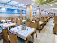 Jasna restauracja w hotelu GHT Oasis Tossa z ustawionymi stolikami