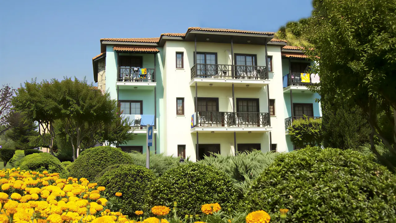 Budynek hotelu Gypsophila Holiday Village otoczony zielenią i kwiatami