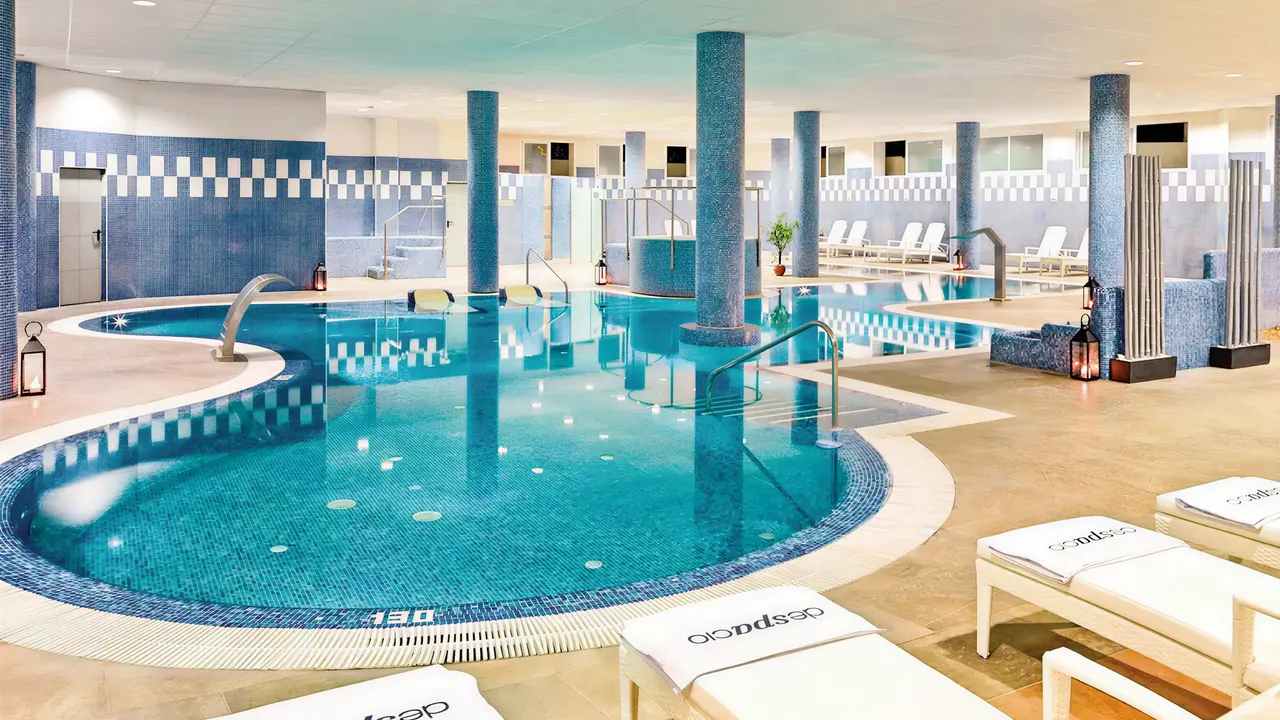 Kryty basen w H10 Estepona Palace z leżakami