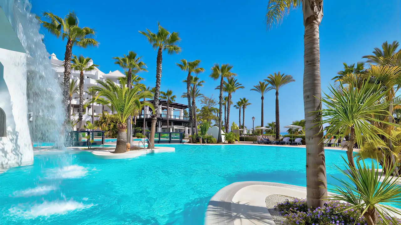 Basen z wodospadem i palmami w H10 Estepona Palace