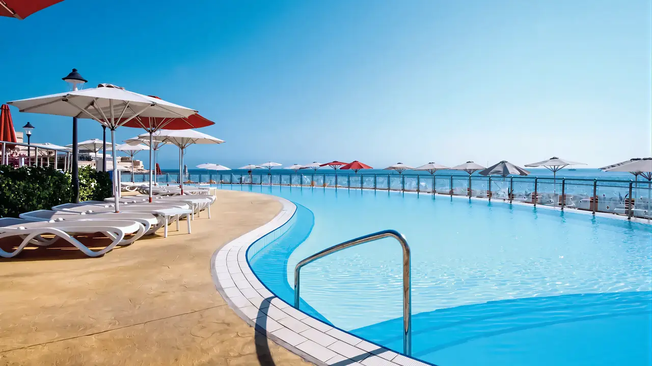 Basen z leżakami i parasolami w Hilton Malta