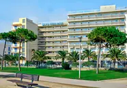 Budynek hotelu HTop Pineda Palace z trawnikiem i palmami