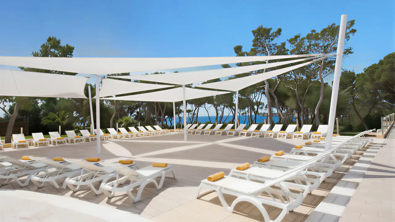 Leżaki pod białym zadaszeniem w Iberostar Waves Club Cala Barca