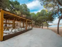 Taras z meblami Iberostar Waves Club Cala Barca przy piaszczystej plaży