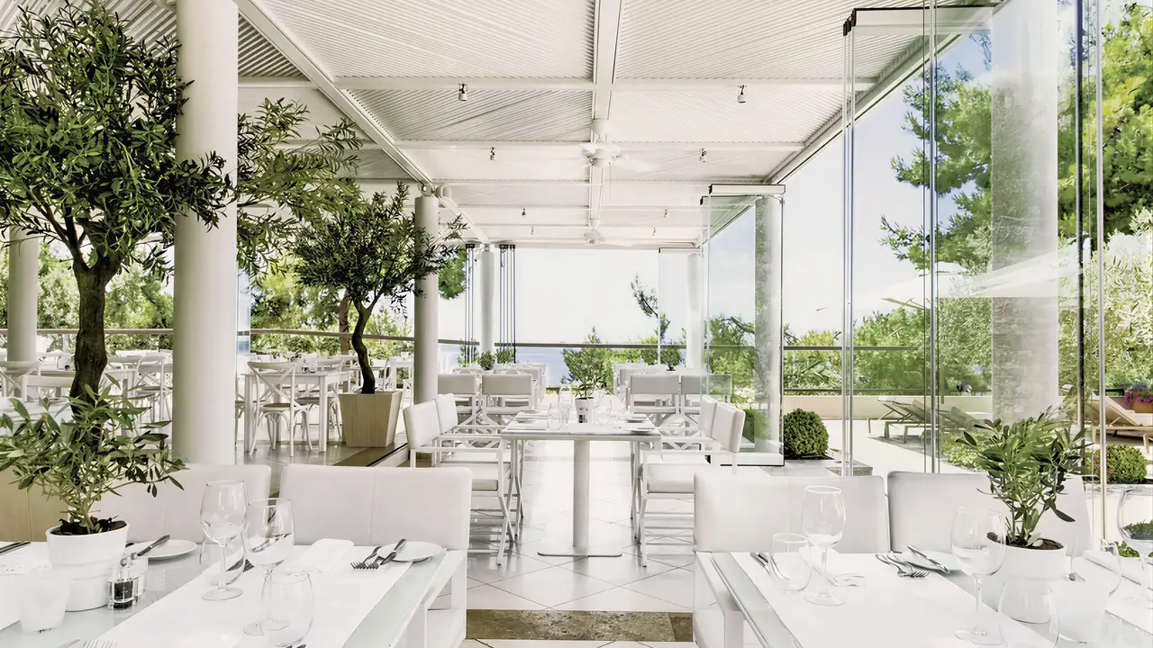 Jasna restauracja w Ikos Oceania z białymi stołami