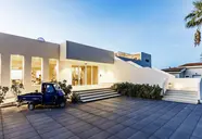 Nowoczesna fasada budynku La Conchiglia Suites & Spa z niebieskim samochodem