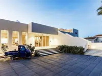Nowoczesna fasada budynku La Conchiglia Suites & Spa z niebieskim samochodem