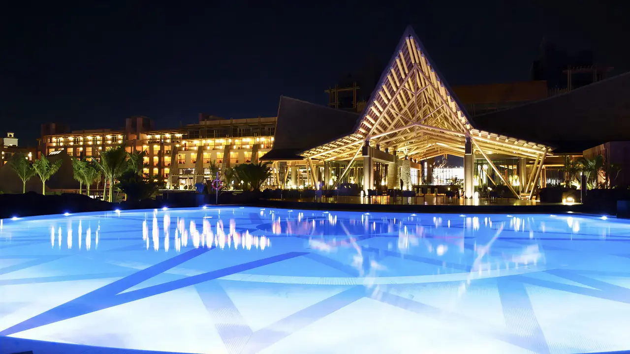 Nocna panorama budynku Lopesan Baobab Resort z podświetlanym basenem