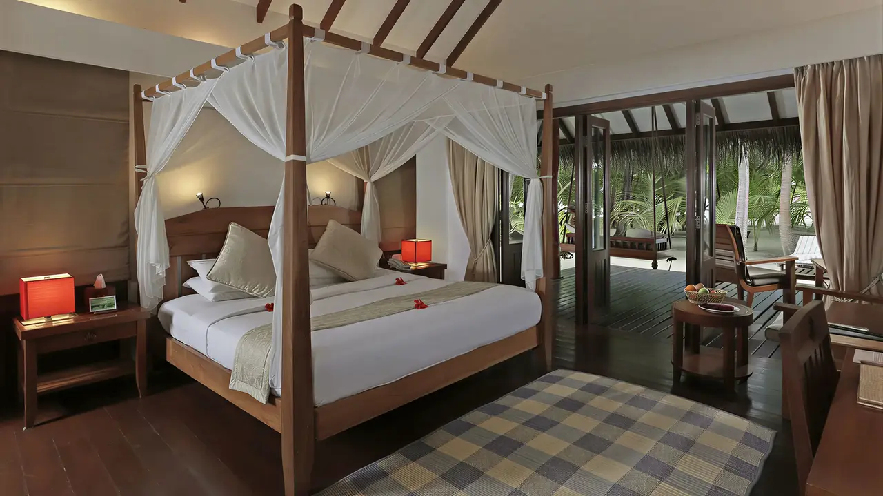 Sypialnia z łóżkiem z baldachimem w Medhufushi Island Resort