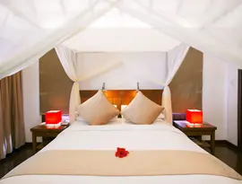 Sypialnia z łóżkiem z baldachimem w Medhufushi Island Resort