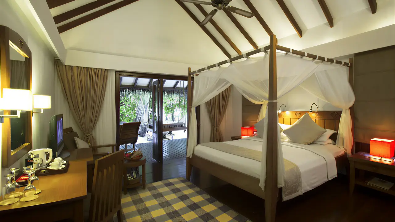 Sypialnia z łóżkiem z baldachimem w Medhufushi Island Resort