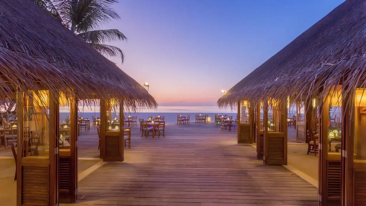 Taras z krytymi altanami w Meeru Island Resort nad morzem