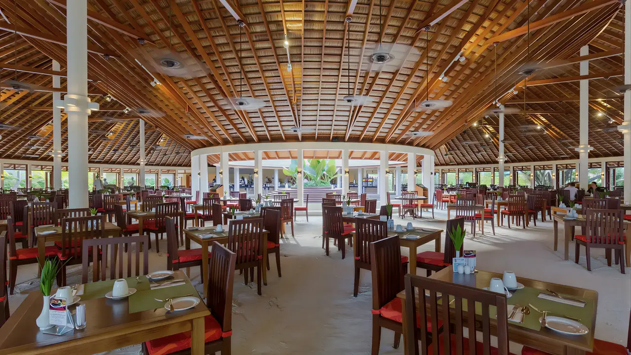 Restauracja w Meeru Island Resort z drewnianymi stołami i krzesłami