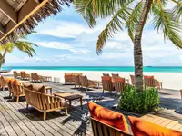 Drewniany taras z leżakami w Meeru Island Resort przy plaży