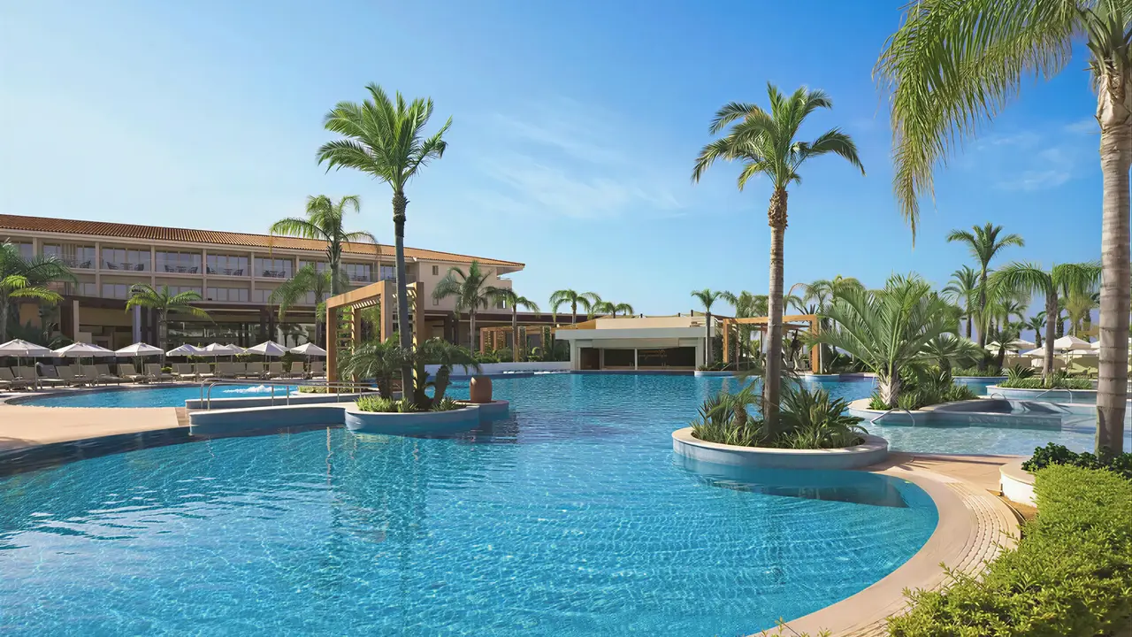 Basen w hotelu Olympic Lagoon Resort Paphos z palmami