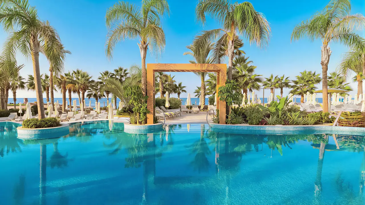 Basen z palmami w Olympic Lagoon Resort Paphos