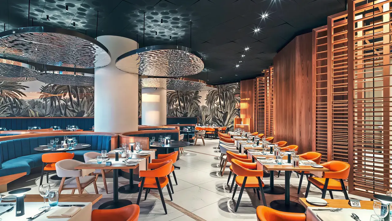 Elegancka restauracja w Olympic Lagoon Resort Paphos z pomarańczowymi krzesłami