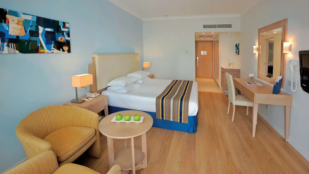 Pokój z łóżkiem i fotelem w Olympic Lagoon Resort Paphos