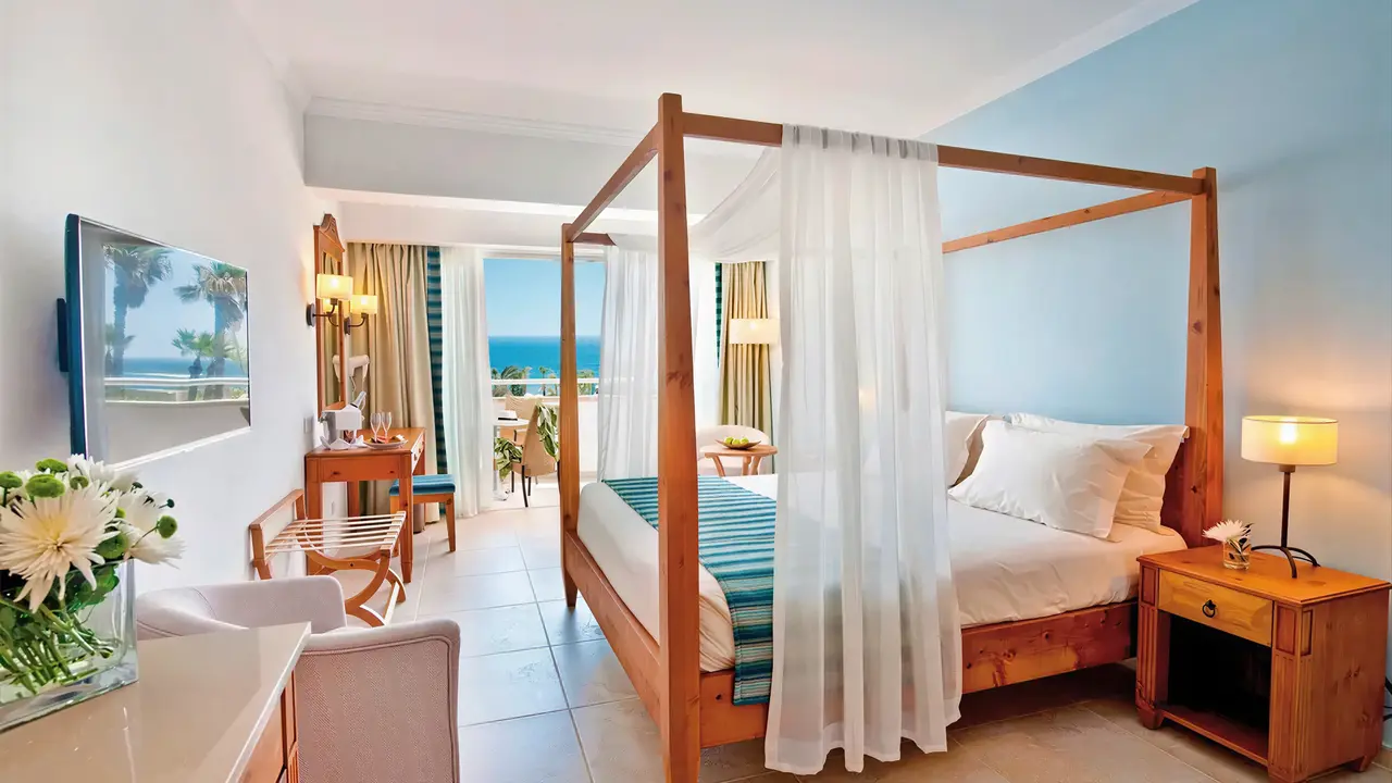Sypialnia z łóżkiem z baldachimem w Olympic Lagoon Resort Paphos