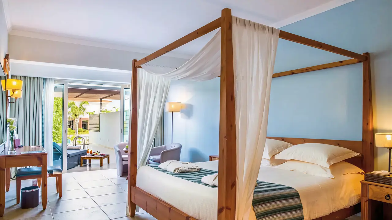 Sypialnia z łóżkiem z baldachimem w Olympic Lagoon Resort Paphos