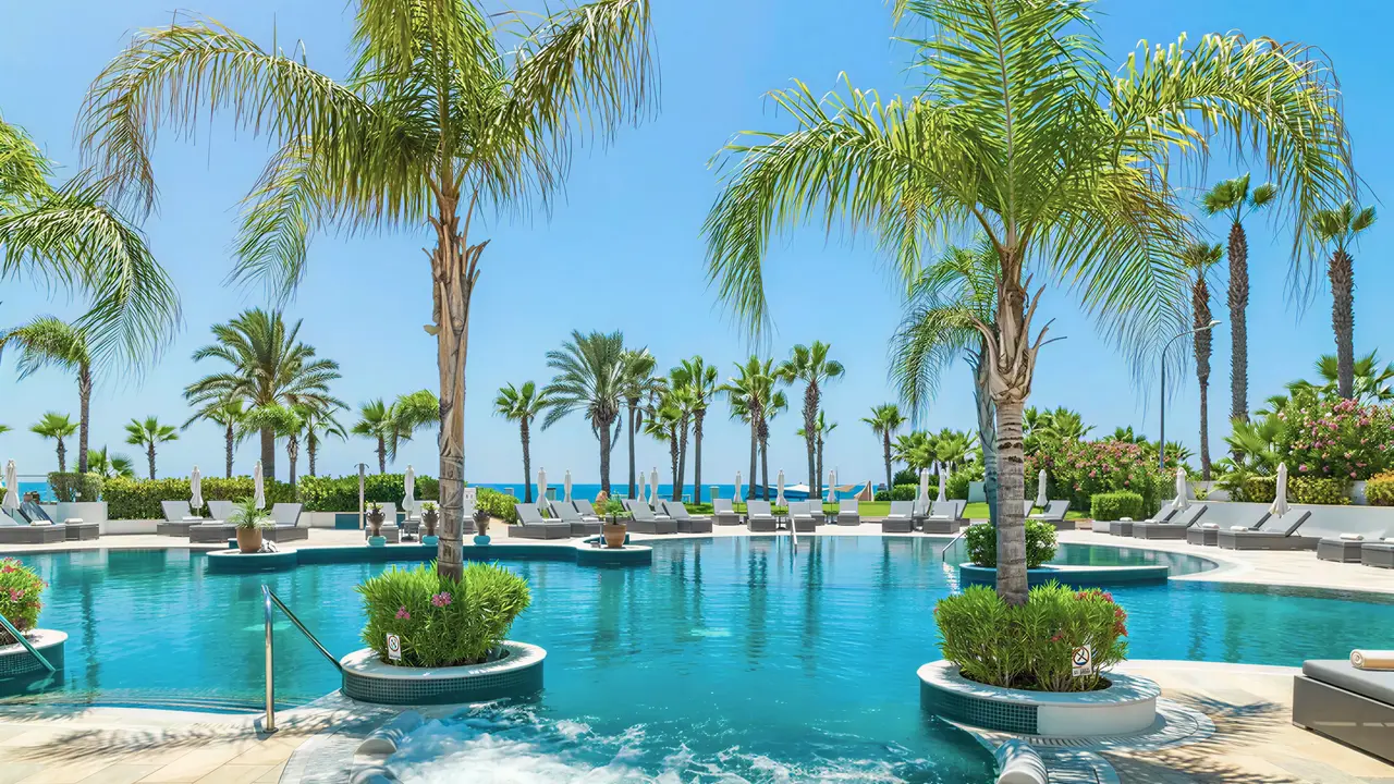 Basen i jacuzzi w Olympic Lagoon Resort Paphos z palmami