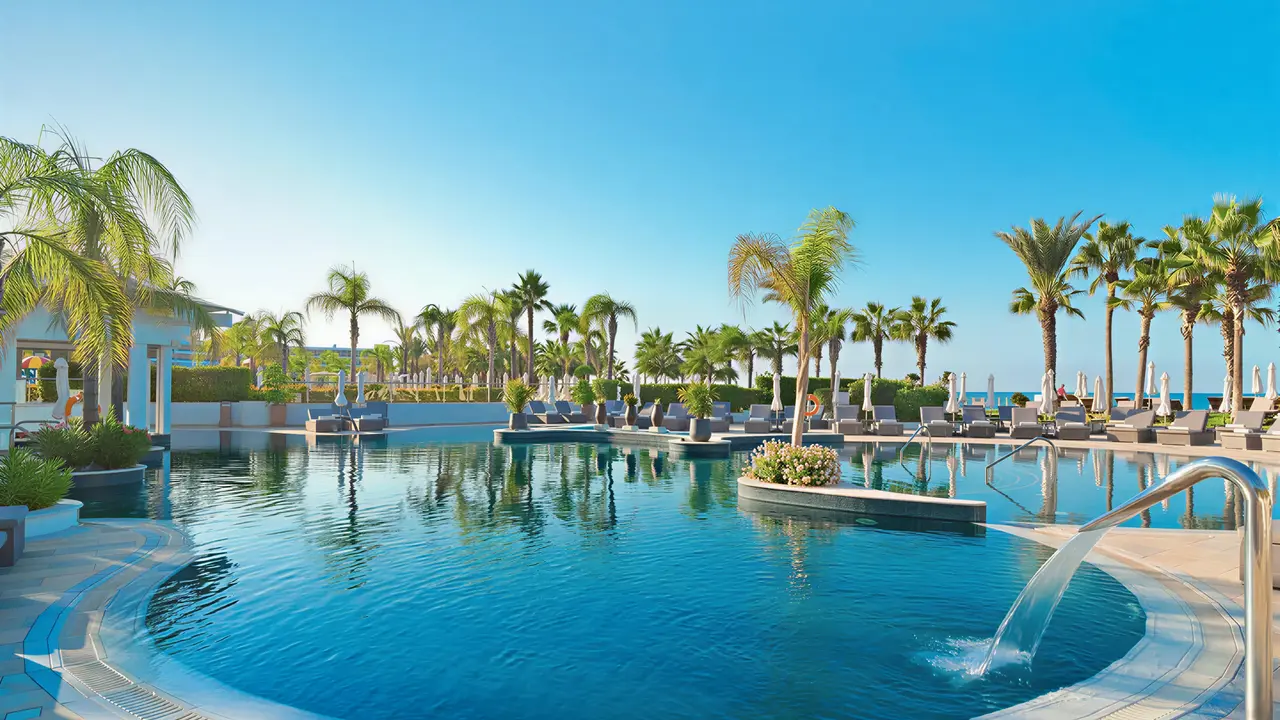 Basen z leżakami w Olympic Lagoon Resort Paphos