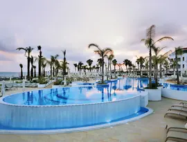 Basen zewnętrzny z leżakami w Olympic Lagoon Resort Paphos