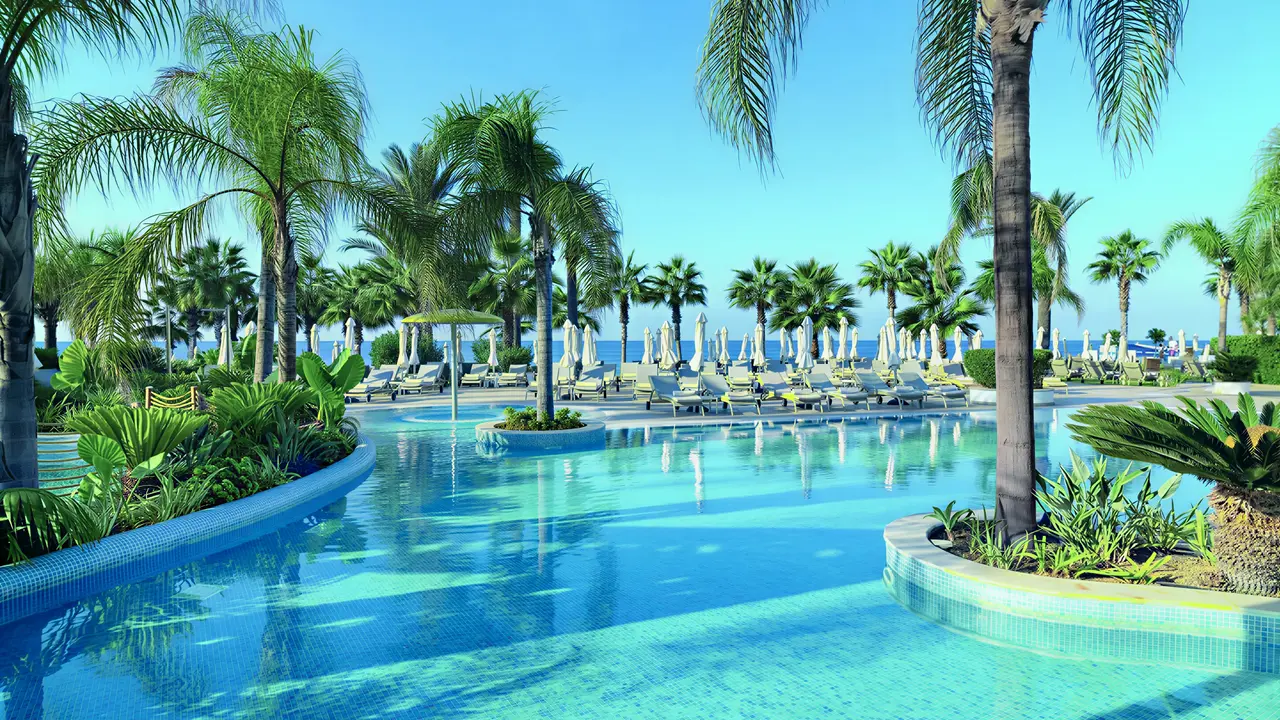 Basen z palmami w Olympic Lagoon Resort Paphos