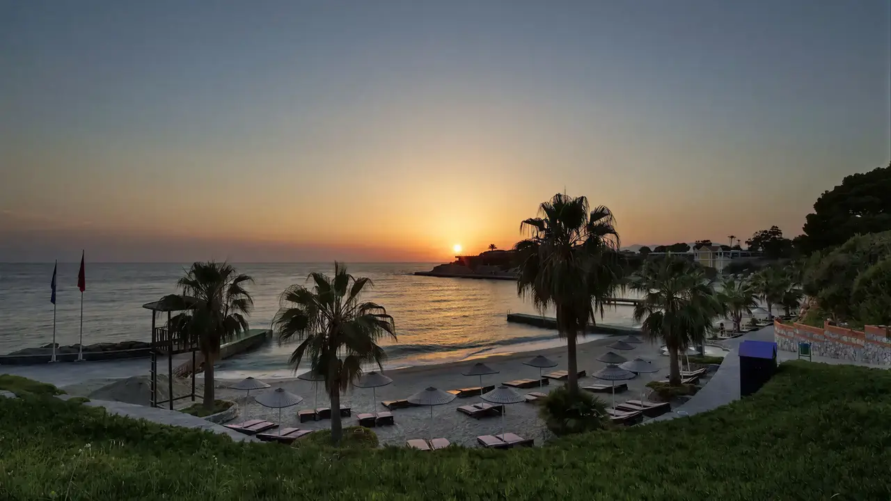 Plaża z leżakami w Pine Bay Holiday Resort podczas zachodu słońca