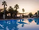Basen w Pine Bay Holiday Resort otoczony palmami o zmierzchu
