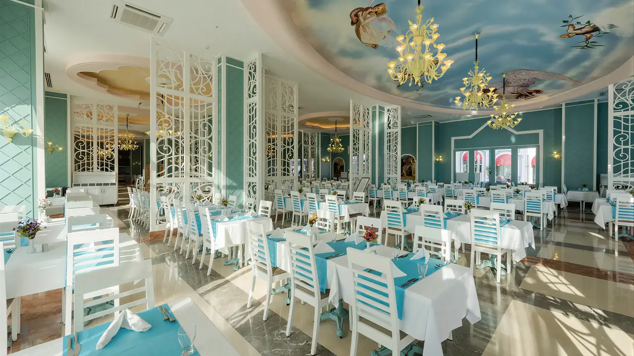 Jasna restauracja w Quattro Beach Spa z białymi stolikami