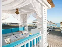 Pawilon plażowy w Quattro Beach Spa z niebieskimi siedziskami